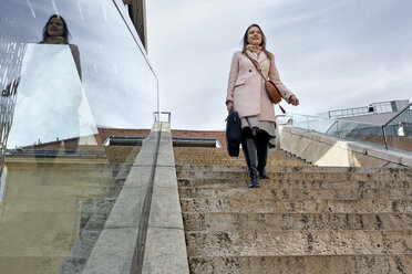 Österreich, Wien, junge Geschäftsfrau, die im MuseumsQuartier die Treppe hinuntergeht - ZEDF01936