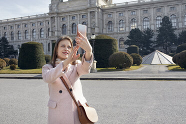 Österreich, Wien, Porträt einer lächelnden jungen Frau, die ein Selfie mit ihrem Smartphone macht - ZEDF01942