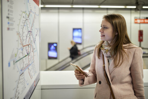 Österreich, Wien, lächelnde junge Frau, die in einer U-Bahn-Station auf eine Karte schaut - ZEDF01951
