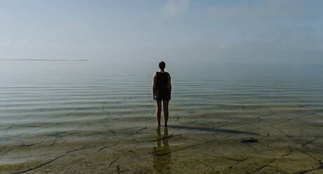 Rear view of woman looking at sea while standing against sky - CAVF61990