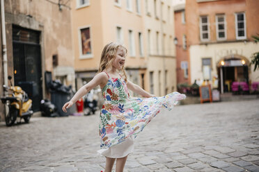 Happy niedlichen Mädchen trägt Kleid Spinnerei auf der Straße gegen Gebäude in der Stadt - CAVF62013