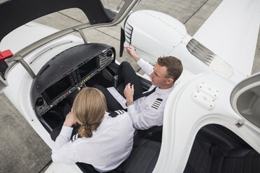 High angle view of male pilot guiding trainee in airplane at airport runway - CAVF62040