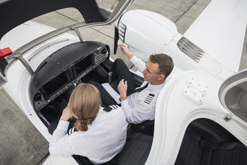 Hoher Blickwinkel des männlichen Piloten, der einen Flugschüler in einem Flugzeug auf der Startbahn eines Flughafens führt - CAVF62040