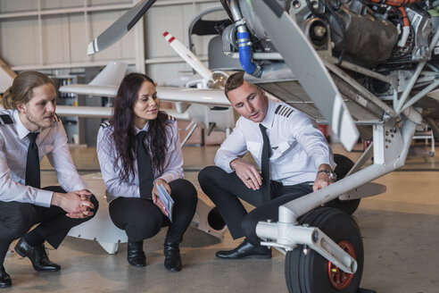 Ingenieur zeigt Auszubildenden im Hangar das Rad eines Flugzeugs - CAVF62050