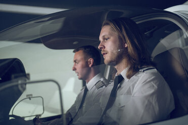 Side view of male pilot with trainee flying in flight simulator - CAVF62058