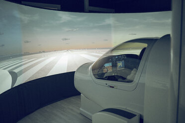 Side view of male trainee flying flight simulator seen through windshield - CAVF62061