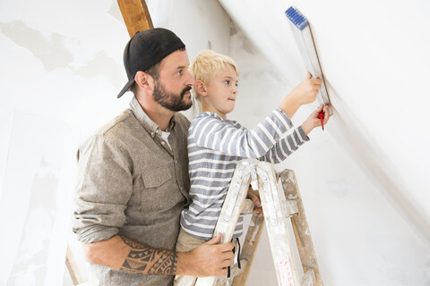 Vater und Sohn arbeiten am Dachbodenausbau mit Hilfe der Wasserwaage, lizenzfreies Stockfoto