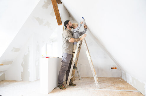 Vater und Sohn arbeiten am Dachbodenausbau mit Hilfe der Wasserwaage - MFRF01173