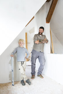 Portrait of smiling father and son working on loft conversion - MFRF01184