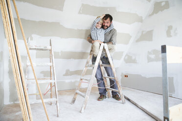 Porträt eines glücklichen Vaters und seines Sohnes bei der Arbeit am Dachbodenausbau - MFRF01188