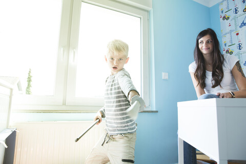 Mutter beobachtet Sohn beim Spielen im Kinderzimmer, lizenzfreies Stockfoto