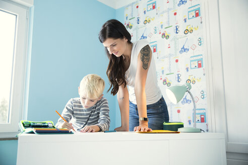 Mother helping son doing homework at desk - MFRF01210