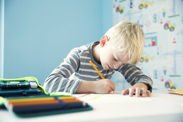 Konzentrierter Junge bei den Hausaufgaben am Schreibtisch im Kinderzimmer - MFRF01218