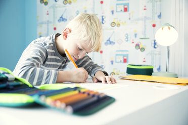 Konzentrierter Junge bei den Hausaufgaben am Schreibtisch im Kinderzimmer - MFRF01219