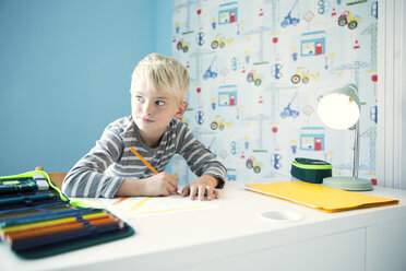 Junge macht Hausaufgaben am Schreibtisch im Kinderzimmer - MFRF01220