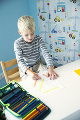 Junge zeichnet auf Papier am Schreibtisch im Kinderzimmer - MFRF01222