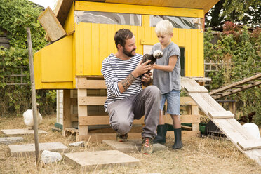 Vater und Sohn mit polnischen Hühnern im Hühnerstall im Garten - MFRF01245