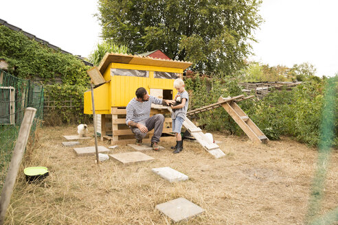 Vater und Sohn mit polnischen Hühnern im Hühnerstall im Garten - MFRF01246