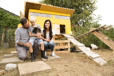 Portrait of happy family with Polish chicken at chickenhouse in garden - MFRF01251