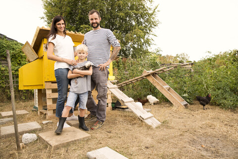 Portrait of confident family with Polish chicken at chickenhouse in garden stock photo