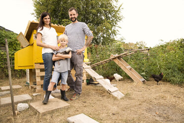 Porträt einer selbstbewussten Familie mit polnischen Hühnern im Hühnerstall im Garten - MFRF01254