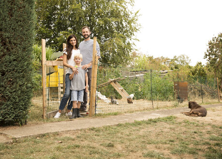Porträt einer selbstbewussten Familie vor einem Hühnerstall im Garten - MFRF01269