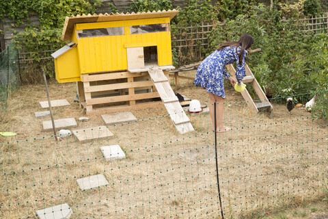 Frau füttert Hühner im Hühnerstall im Garten, lizenzfreies Stockfoto