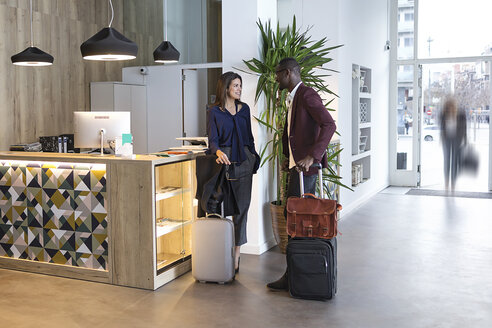 Business people waiting with luggage at hotel reception - JSRF00147