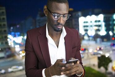 Jungunternehmer, der auf der Hotelterrasse auf seinen Termin wartet und sein Smartphone benutzt - JSRF00151