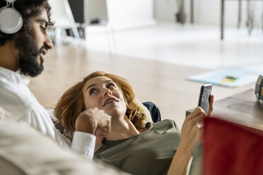 Couple relaxing on couch, planning their road trip - AFVF02525