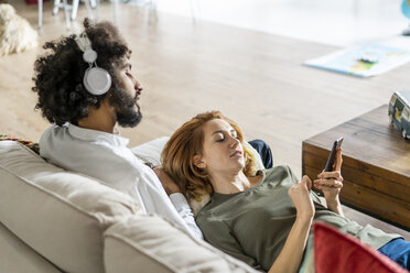 Couple relaxing on couch, planning their road trip - AFVF02526