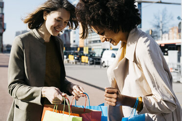 Zwei glückliche Frauen mit Einkaufstaschen in der Stadt bei der Kontrolle des Einkaufs - JRFF02772