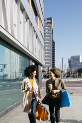 Zwei glückliche Frauen mit Einkaufstaschen und Kaffee zum Mitnehmen beim Spaziergang in der Stadt - JRFF02774