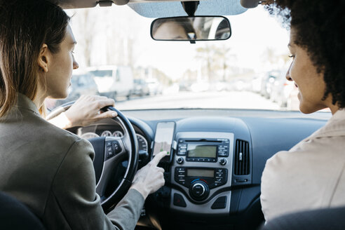 Zwei Frauen fahren in einem Auto durch die Stadt und nutzen eine telefonische Navigations-App - JRFF02795