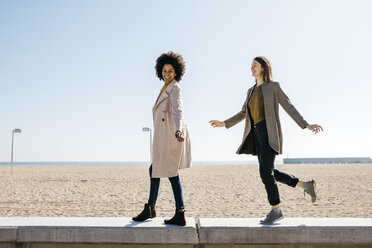 Zwei glückliche Freunde, die auf der Promenade spazieren gehen und ihre Freizeit genießen - JRFF02808