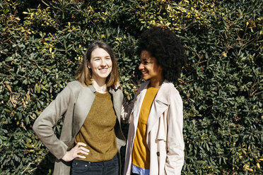 Portrait of two happy women in front of a hedge - JRFF02817