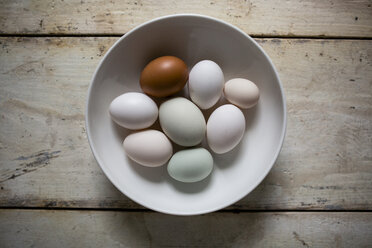 Overhead view of eggs in bowl on wooden table - CAVF62096