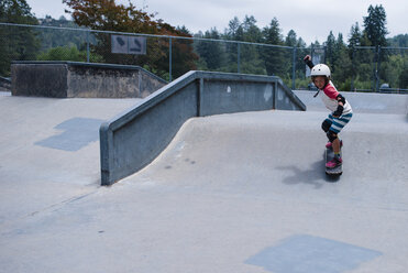 Side view of girl skateboarding on sports ramp against trees at park - CAVF62120
