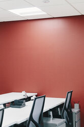 High angle view of chairs and desks arranged by red wall in modern creative office - CAVF62123