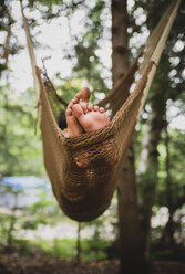 Low section of boy relaxing on hammock in forest - CAVF62153