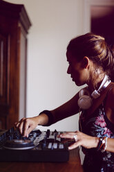 Side view of female DJ mixing sound while sitting in recording studio - CAVF62188