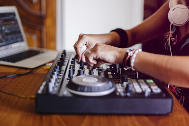 Midsection of female DJ using laptop computer while mixing sound in recording studio - CAVF62189