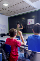 Boy explaining mathematics to friends in classroom - CAVF62196