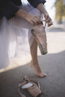 Tiefschnitt einer Ballerina mit zerrissenen Ballettschuhen auf einer Straße in der Stadt - CAVF62211