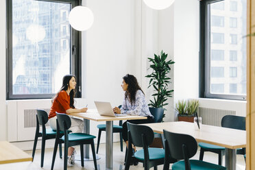 Weibliche Kollegen beim Brainstorming, während sie auf Stühlen am Schreibtisch im Büro sitzen - CAVF62270