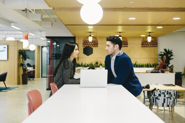 Business people with laptop computer on table discussing in cafeteria at office - CAVF62277