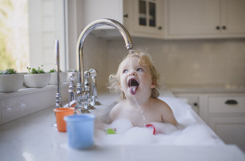 Cute shirtless Mädchen trinken Wasser aus dem Wasserhahn beim Baden im Waschbecken zu Hause - CAVF62283