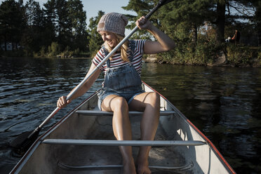 Happy woman rowing boat on lake at Algonquin Provincial Park - CAVF62291