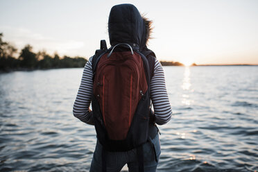 Rückansicht einer Frau mit Rucksack am Seeufer gegen den klaren Himmel bei Sonnenuntergang - CAVF62308