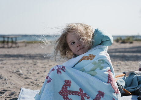 Nettes Mädchen mit unordentlichem Haar, das wegschaut, während es am Strand sitzt - CAVF62312